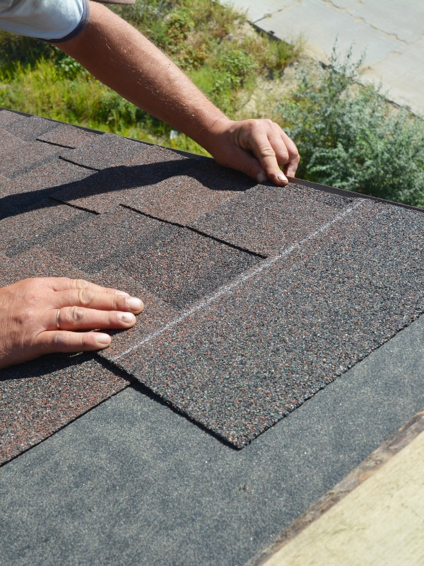 Hands installing roof shingles