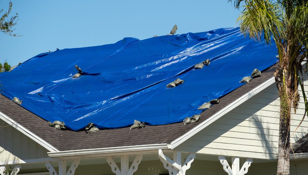 A damaged roof covered in a blue tarp.