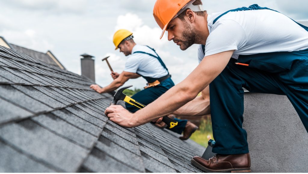 Professional roofers restore a roof on a cloudy, overcast day.