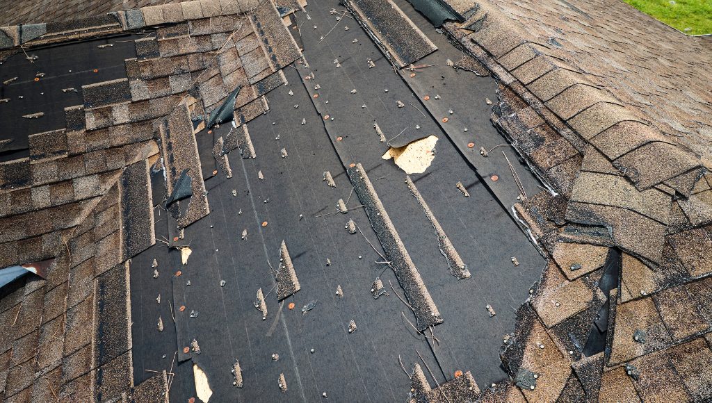 A wind damaged roof with many missing shingles.